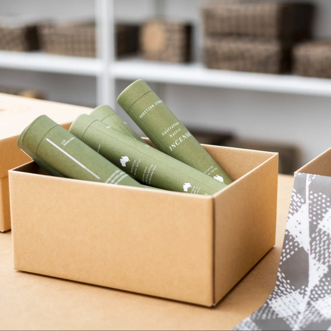 Green cylindrical containers with white text in a cardboard box on a wooden surface.